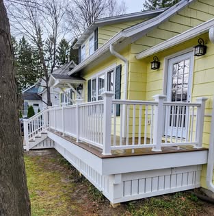 Finished deck with white railing along a yellow home